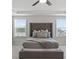 Well-lit main bedroom with an upholstered bed, a tray ceiling, and large windows providing natural light at 221 Begonia Way, Mcdonough, GA 30253