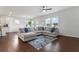 Open-concept living room with a large sectional sofa, hardwood floors, natural light, and a view of the kitchen at 221 Begonia Way, Mcdonough, GA 30253