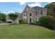 Beautiful brick home featuring a lush green lawn, mature trees, and a meticulously landscaped front yard at 3143 Denton Ne Pl, Roswell, GA 30075