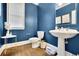 Stylish powder room with blue walls, hardwood floors, and a pedestal sink at 3143 Denton Ne Pl, Roswell, GA 30075