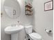 Bright half bathroom featuring a pedestal sink, oval mirror, and decorative wall shelves at 1539 Creek Bend Ln, Lawrenceville, GA 30043
