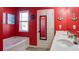 Vibrant bathroom featuring double sinks, a soaking tub, red walls, and nautical decor for a unique and playful aesthetic at 156 Woodhouse Cir, Acworth, GA 30102