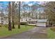 View of the home's front, long driveway, lawn, and mature trees providing shade at 2325 Lago Dr, Jonesboro, GA 30236