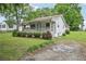 Well-maintained home with a covered front porch and gravel driveway surrounded by a green lawn at 6648 Florence Dr, Lithia Springs, GA 30122