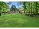 Expansive backyard featuring lush green lawn, mature trees, and a home with a spacious deck at 305 Jasmine Ct, Woodstock, GA 30189