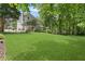 Expansive backyard with lush lawn, mature trees, and screened porch on the home's exterior at 305 Jasmine Ct, Woodstock, GA 30189