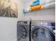 Practical laundry room equipped with modern washer and dryer units and shelving at 6637 Chason Woods Ct, Jonesboro, GA 30238