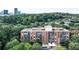 Aerial view of a brick apartment building surrounded by lush greenery and a distant city skyline at 130 26Th St # 402, Atlanta, GA 30309