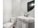 A half bathroom features a toilet, pedestal sink and modern round mirror at 2505 Astaire Nw Ct, Atlanta, GA 30318