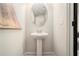 Charming powder room featuring a pedestal sink, oval mirror, and modern artwork at 2505 Astaire Nw Ct, Atlanta, GA 30318