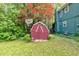 Backyard view featuring a red storage shed and basketball hoop, surrounded by lush landscaping at 316 Shiloh Hills Nw Dr, Kennesaw, GA 30144