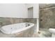 Bathroom featuring a deep soaker tub, stand up shower, and marbled stone-style tile at 3781 Cherokee Trl, Suwanee, GA 30024