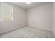 A well-lit bedroom with neutral carpet, trim, and wall paint, featuring a window for natural light at 1682 Juniper Berry Way, Loganville, GA 30052