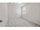 A light-filled bedroom with neutral carpet, white walls, trim, door, and a window at 1682 Juniper Berry Way, Loganville, GA 30052
