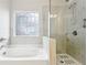 Bright bathroom with a stylish tub with a decorative window, complemented by a frameless glass shower at 306 Lark Ln, Canton, GA 30115