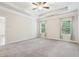 An airy bedroom featuring a tray ceiling, a ceiling fan, plush carpet, and large windows with leafy green views at 306 Lark Ln, Canton, GA 30115