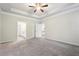 A large bedroom with access to a bathroom, a bedroom, a tray ceiling, a ceiling fan, and neutral carpet at 306 Lark Ln, Canton, GA 30115