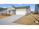 Front exterior showcasing driveway and lawn leading up to the charming, single-story home's two-car garage at 1783 Juniper Berry Way, Loganville, GA 30052