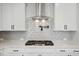 Modern kitchen featuring stainless steel hood, gas range, sleek white cabinets and backsplash at 1783 Juniper Berry Way, Loganville, GA 30052
