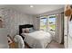 Cozy bedroom with a patterned accent wall, queen-size bed, and a view of the outdoors at 99 Oxford Ln, Kingston, GA 30145