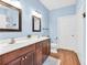 A bathroom with blue walls, double sink vanity, a large mirror, wood floors, and white toilet at 2318 Chancery Mill Ln, Buford, GA 30519