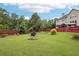 Lush backyard with mature trees, decorative flowerbeds, and a charming red fence at 2120 Cain Commons Dr, Dacula, GA 30019