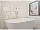 Close-up of a sleek, freestanding bathtub with a stylish faucet and tiled wall at 2186 Park Terrace, College Park, GA 30337