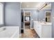 Main bathroom featuring double sinks, white cabinets, and a separate bathtub at 2102 Braswell Ln, Loganville, GA 30052