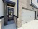 Close-up of a townhome entrance, showcasing brickwork, a black front door, and a two-car garage at 5704 Urban Village Way # 3, Tucker, GA 30084