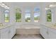 Bright bathroom features a garden tub with marble surround, double vanities, and large windows for natural light at 3030 Berry Rd, Loganville, GA 30052