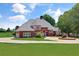 Stately brick home featuring a circular driveway, lush landscaping, and a pristine green lawn at 3030 Berry Rd, Loganville, GA 30052