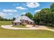 Classic brick home with a circular driveway, manicured garden, and a sprawling green lawn under a sunny sky at 3030 Berry Rd, Loganville, GA 30052