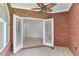 Indoor patio area featuring a brick wall, ceiling fan, and white-framed entry doors at 3030 Berry Rd, Loganville, GA 30052
