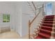 Bright foyer staircase with red patterned stair runner and traditional wood banister at 3030 Berry Rd, Loganville, GA 30052