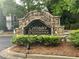 Stone entrance sign for Cottages of Woodstock, surrounded by lush landscaping at 329 Acuba Vw, Woodstock, GA 30188
