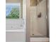 Bathroom featuring tub, walk-in shower, and window with great natural light, with white tile at 121 Camdyn Cir, Woodstock, GA 30188