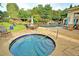 Relaxing hot tub area with a stone patio, surrounded by lush landscaping and access to the community pool at 2771 Middlecreek Way, Cumming, GA 30041