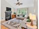 Cozy living room with a fireplace, ceiling fan, and lots of natural light at 387 Rose Creek Pl, Woodstock, GA 30189