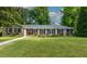 Charming brick home with a well-manicured lawn, black shutters, and colorful flowerbeds in the front yard at 690 Glenforest Rd, Sandy Springs, GA 30328