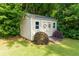 Charming storage shed with double doors, decorative wreaths, and surrounded by lush greenery at 690 Glenforest Rd, Sandy Springs, GA 30328