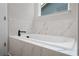 Relaxing soaker tub surrounded by marble-look tile and a garden window at 3564 Arrow Root Cir, Loganville, GA 30052