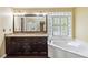 Bright bathroom with granite countertop, dark wood cabinets, soaking tub, and decorative window at 4002 Turnstone Nw Dr, Kennesaw, GA 30152