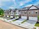 Row of townhomes featuring brick and siding exteriors, two-car garages, and neatly landscaped front yards under a blue sky at 5706 Urban Village Way # 4, Tucker, GA 30084