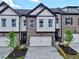 Modern townhome showcasing a two-car garage, gray brick, white siding, and black trim against a blue sky at 5706 Urban Village Way # 4, Tucker, GA 30084