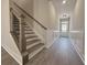 Staircase with rod iron balusters and stained wood railing and treads; door visible at end of hall at 5706 Urban Village Way # 4, Tucker, GA 30084