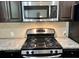 Close up of the stainless steel stove and microwave with dark cabinets and granite countertops at 2249 Knoxhill Se Vw, Smyrna, GA 30082