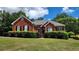 Charming brick home featuring a well-manicured lawn and lush landscaping at 3858 Glenlake Dr, Douglasville, GA 30134