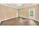 Spacious bedroom featuring tray ceiling, ceiling fan, hardwood floors, and access to a balcony at 214 Kingsley Way, Woodstock, GA 30188