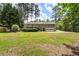 View of the home with an attached garage, a wooden deck, and a large backyard with mature shade trees at 3131 Garden Lane Dr, Marietta, GA 30062