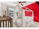 A bedroom features a crib, a canopy bed, and a red accent wall, creating a bright and playful space at 5305 Redfield Way, Cumming, GA 30028